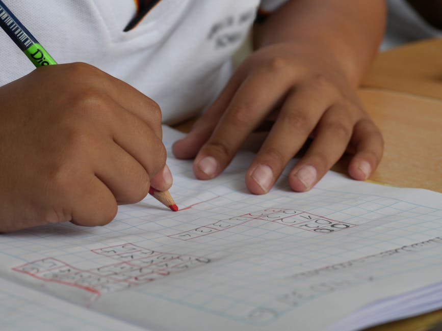 Close-up of a student writing math equations in a notebook with a pencil indoors